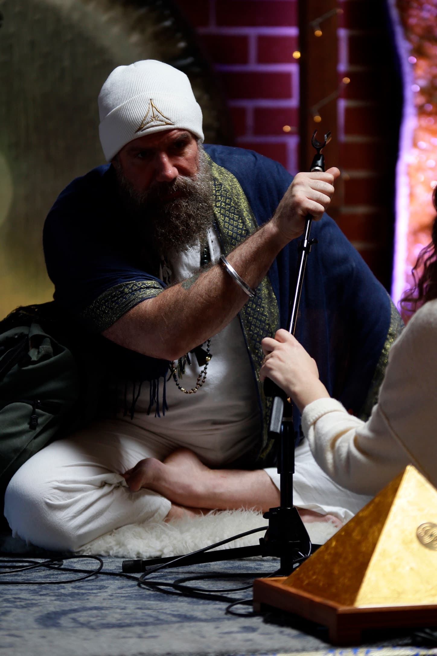 Mikal Vega sets a microphone before a practitioner, transmitting the practice in person.